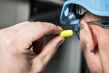 Construction worker using earplugs to help protect hearing in the New England area.